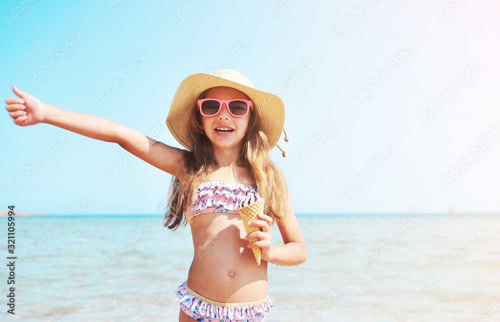 Cute little girl with ice cream has fun on the beach. Summertime concept.