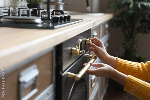 Slika na platnu Woman using modern oven in kitchen, closeup