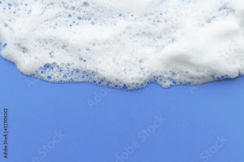 The texture of soap foam flows down from above on a lilac background. The concept of hygiene.