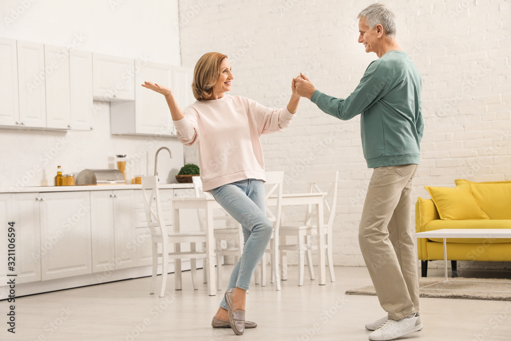 Happy senior couple dancing together in kitchen