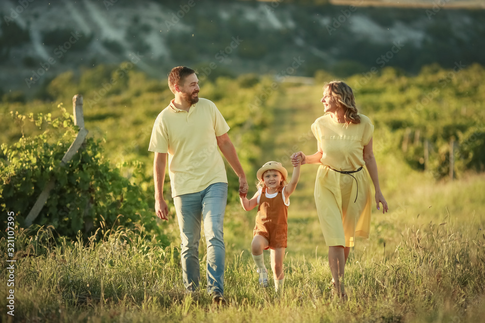 Family of three mom dad and daughter walking in a grape field. Family of three mom dad and daughter walking in a grape field.