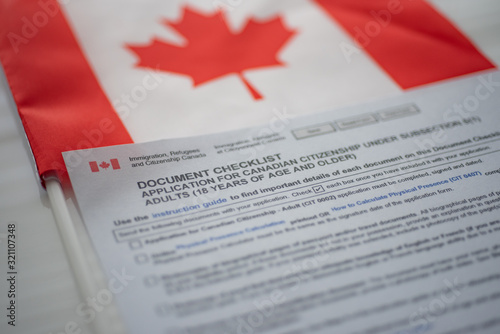 Document check list application for canadian citizenship next to Canadian flag, close up view.