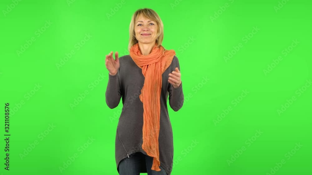 Middle aged blonde woman is clapping her hands. Green screen