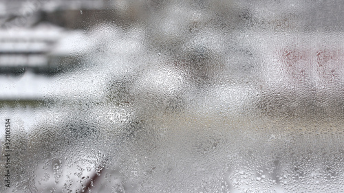 High humidity in the form of condensation on a transparent glass with large drops of natural water. Defective plastic window with condensation