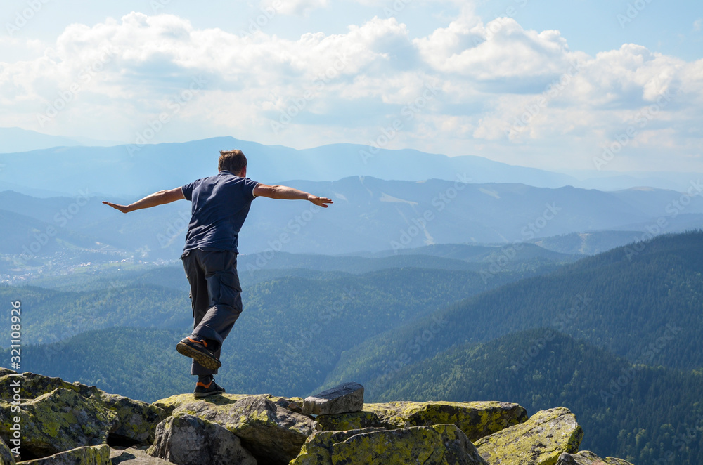 A young hiker on a mountain top stretching his arms like flying. Astonishing landscape of Carpathian in Summer 
