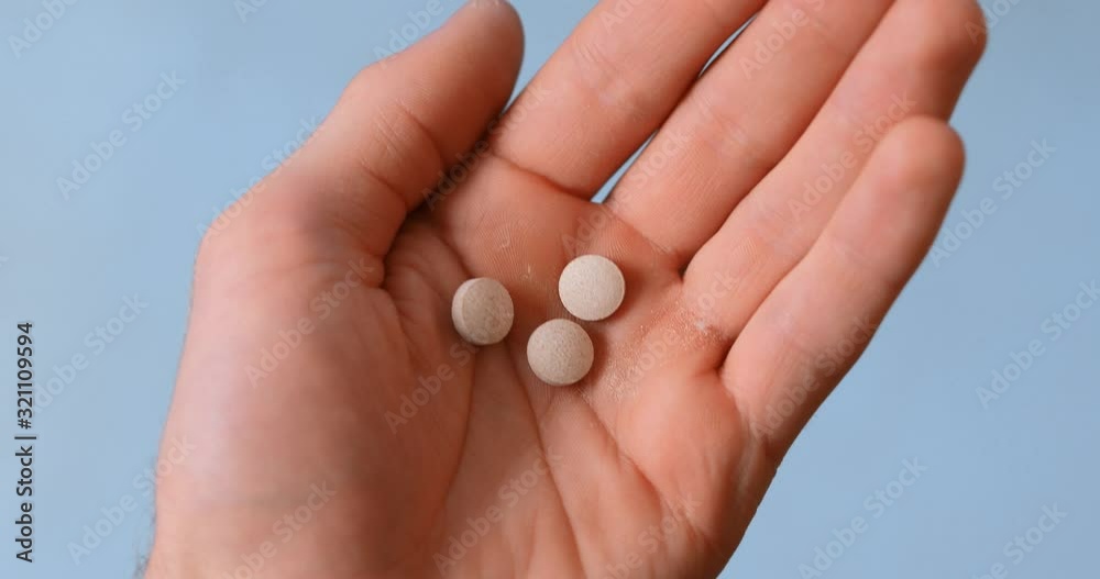 Man pours pills, tablets on a hand, closeup Man pours pills, tablets on a hand, closeup