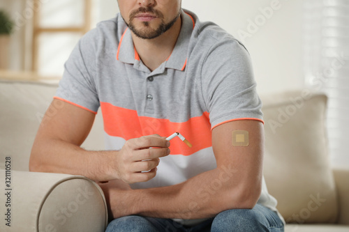 Man with nicotine patch and cigarette at home, closeup photo