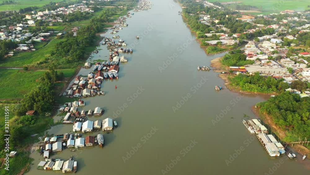 La rivière Bassac, le village flottant de Chau Doc et des rizières en arrière plan éclairés au coucher du Soleil dans le delta du Mékong, au sud du Vietnam