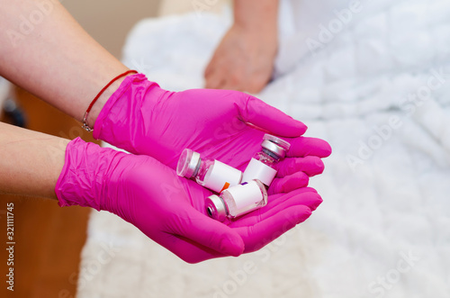 Hands in rubber gloves hold glass ampoules with medicines.