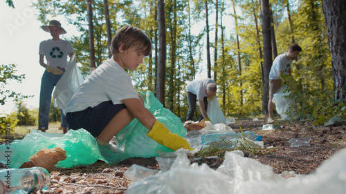 Volunteers activists people in gloves tidying up rubbish in park or forest environment concept stop plastic pollution bag bottle recycle ecology garbage nature altruism care clean close up