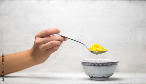 Hand holding spoonful of steamed corn