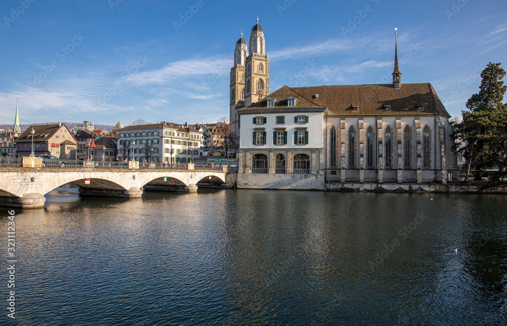 Beautiful view of historic city center of Zurich with famous Fraumunster Church and Munsterbucke crossing river Limmat on a sunny winter day with blue sky, Canton of Zurich, Switzerland.