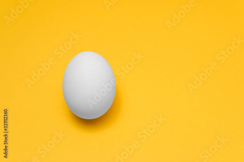one white egg on yellow background on left side for designs, visual art for easter advertise
