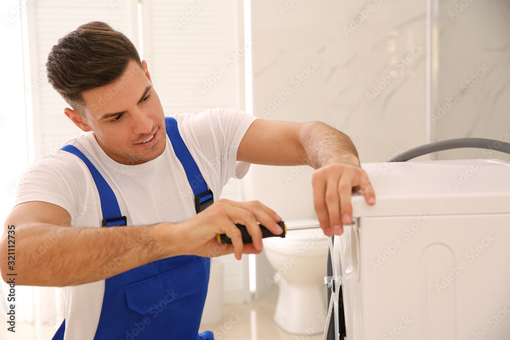 Professional plumber repairing washing machine in bathroom Professional plumber repairing washing machine in bathroom
