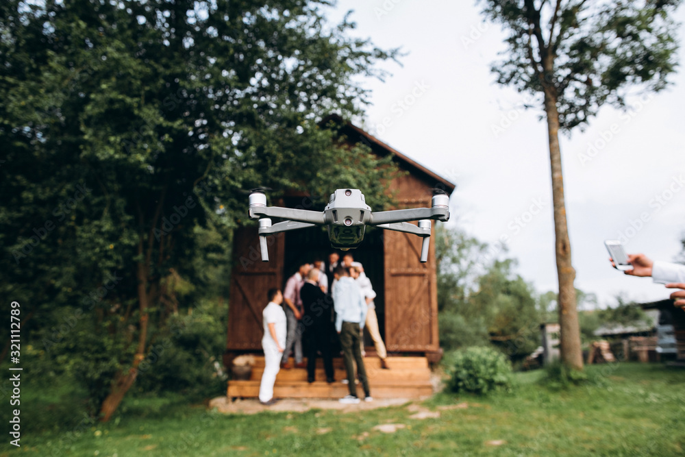 A drone in the air shoots a group of people at a party in the open air