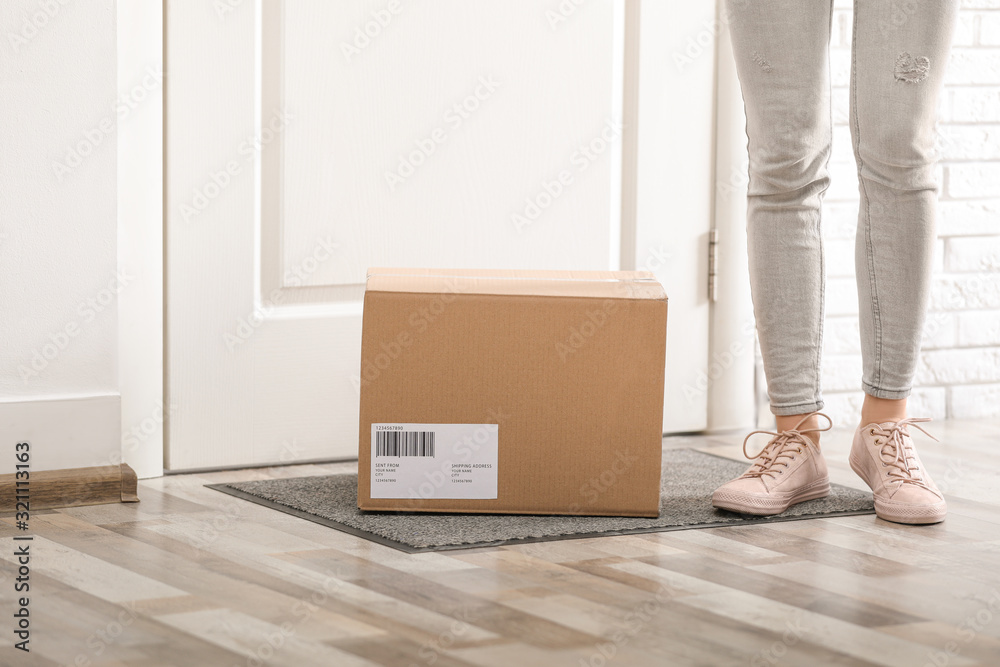 Fototapeta premium Woman with parcel near door, closeup Delivery service