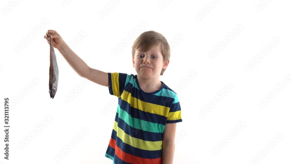 boy posing in studio on a white background with raw fish, grimaces of disgust boy posing in studio on a white background with raw fish, grimaces of disgust