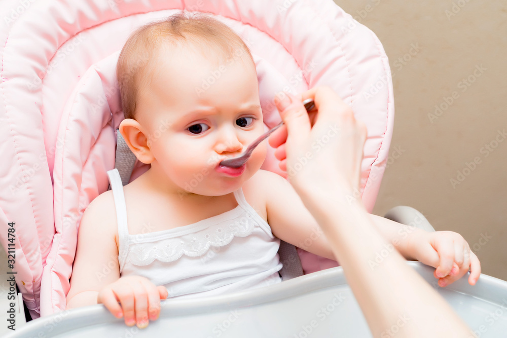 Feeding cute baby girl in pram with spoon Feeding cute baby girl in pram with spoon