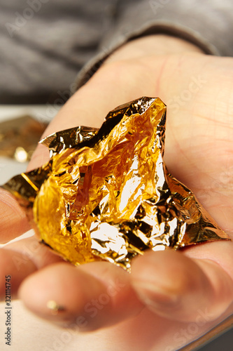 Obraz na plátně Artwork of gilding - sheet of creased gold metal plate in hands