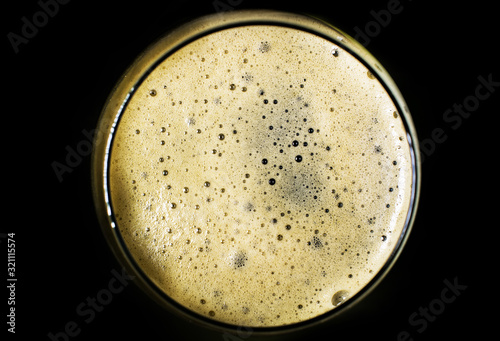 a glass of black beer, on a black background, isolated. Photo taken from above the glass. Foam