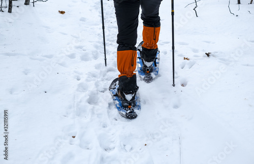 Man in snowshoes with trekking poles is the snow in the forest