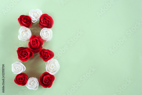 Red and white roses in the form of the number 8 on a green background. Festive background for Valentine's day