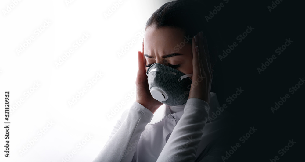 Portrait of young sad female doctor suffering from severe headache, pressing her fingers to temples. Woman in protective respirator. Free space for text. White background. Healthcare concept. Portrait of young sad female doctor suffering from severe headache, pressing her fingers to temples. Woman in protective respirator. Free space for text. White background. Healthcare concept.