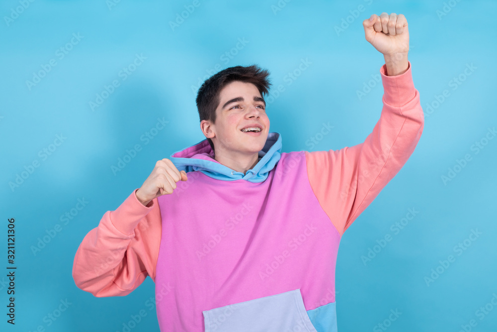 Naklejka premium young teenage man or student isolated with enthusiasm expression isolated on blue background