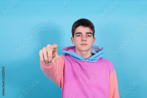 young teenager or student boy with expression of surprise or admiration pointing by hand