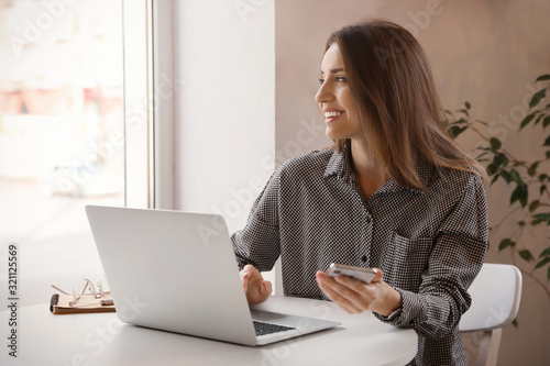 Young blogger working with laptop at table in cafe