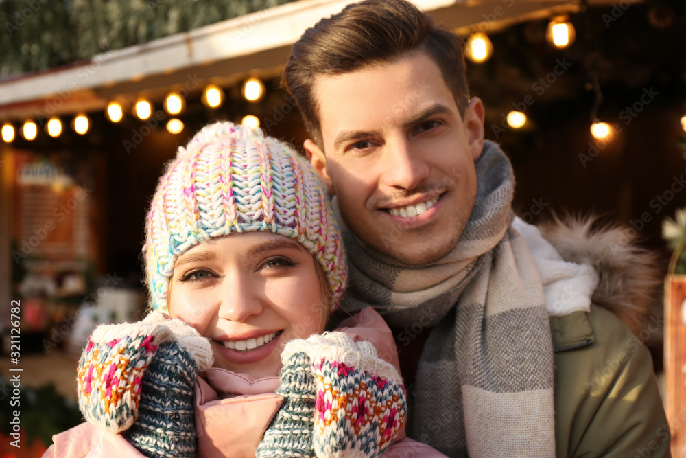 Obraz premium Happy couple in warm clothes at winter fair. Christmas season