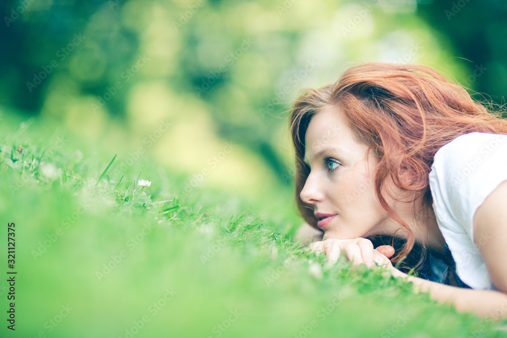 portrait of young red haired woman lying on the grass portrait of young red haired woman lying on the grass