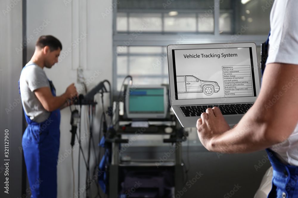 Mechanic with laptop doing car diagnostic at automobile repair shop, closeup. Space for text Mechanic with laptop doing car diagnostic at automobile repair shop, closeup. Space for text