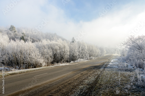 The road to the mountains. Winter landscape with a mountain road in the morning fog. In the early foggy morning, the road to the mountains looks especially mysterious and beautiful.   © Mykhaylo