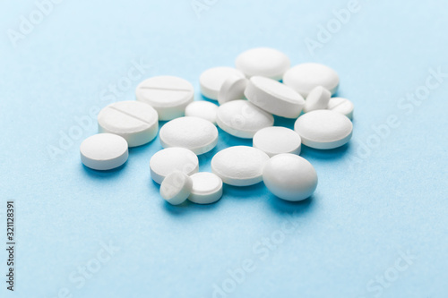 scattered white pills on a blue table. Layout for special offers such as advertising or other ideas. The concept of medicine, pharmacy and healthcare. Space for copy. flat lay for text or logo.