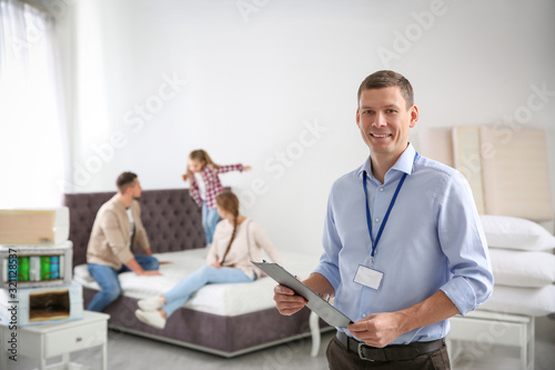 Happy salesman and his clients in mattress store