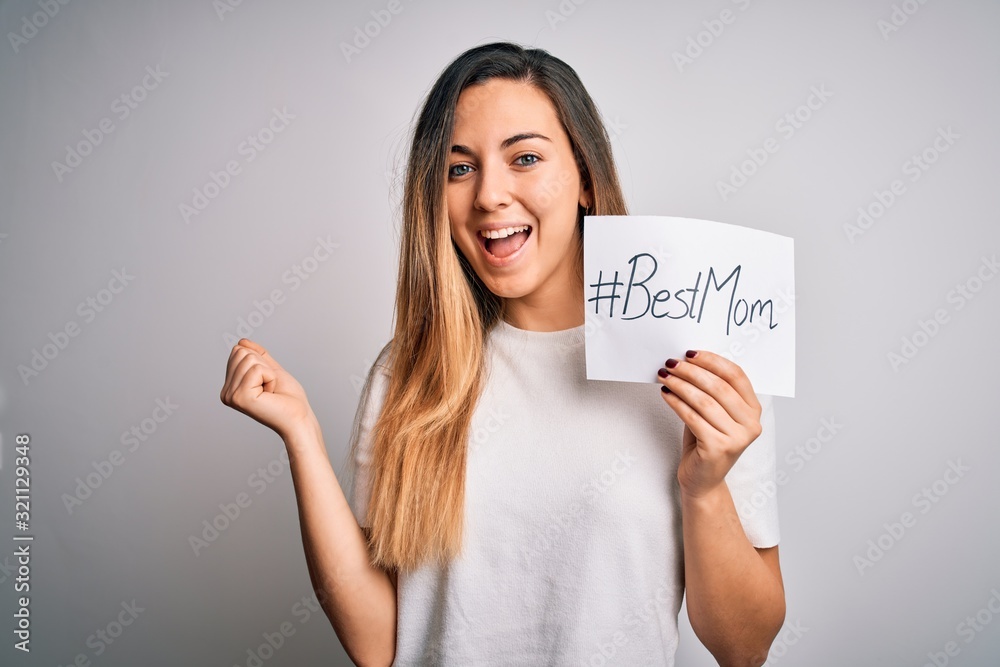 Young beautiful woman holding paper with best mom message celebrating mothers day screaming proud and celebrating victory and success very excited, cheering emotion Young beautiful woman holding paper with best mom message celebrating mothers day screaming proud and celebrating victory and success very excited, cheering emotion