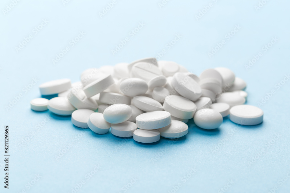 scattered white pills on a blue table. Layout for special offers such as advertising or other ideas. The concept of medicine, pharmacy and healthcare. Space for copy. flat lay for text or logo. scattered white pills on a blue table. Layout for special offers such as advertising or other ideas. The concept of medicine, pharmacy and healthcare. Space for copy. flat lay for text or logo.