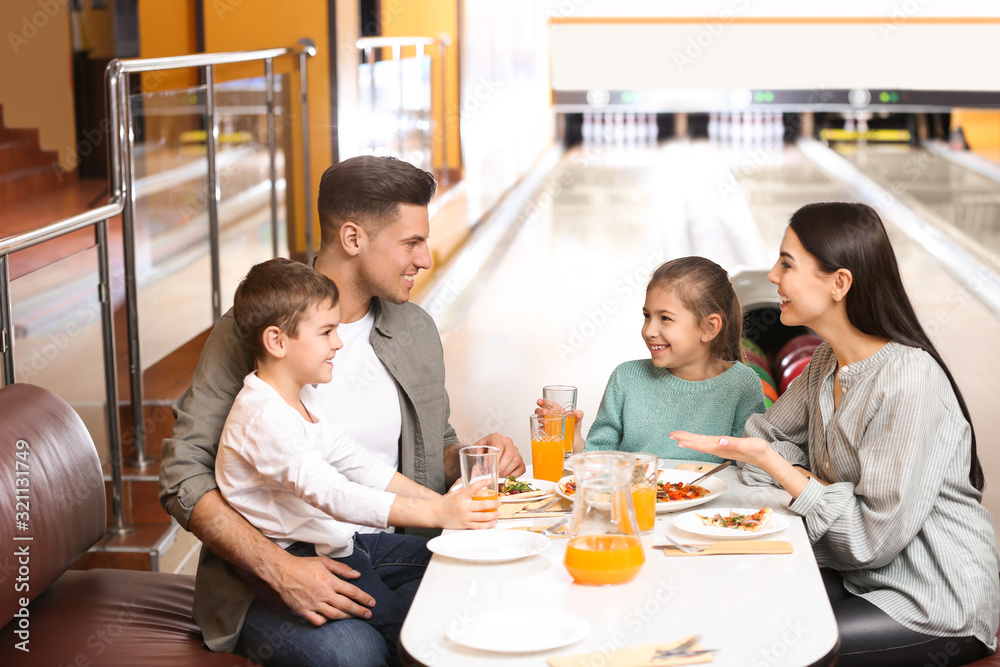Happy family with pizza and drinks in bowling club Happy family with pizza and drinks in bowling club