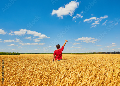 happy farmer, businessman, standing in wheat field with his hands and thumbs up