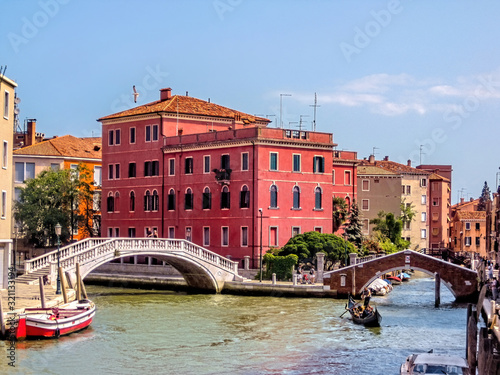 Bridge over a small canal with passing boats, Venice, Italy
