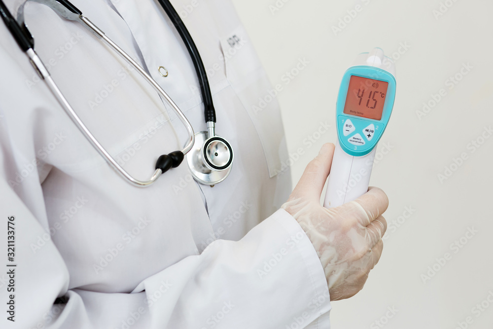 a woman doctor in a white coat and gloves, holding an electronic thermometer  with indicators of high body temperature on a white background Stock Photo  | Adobe Stock