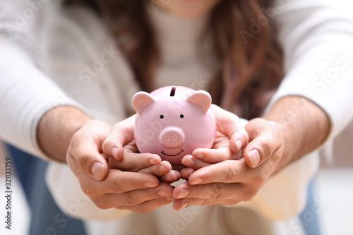 Couple holding pink piggy bank, closeup view