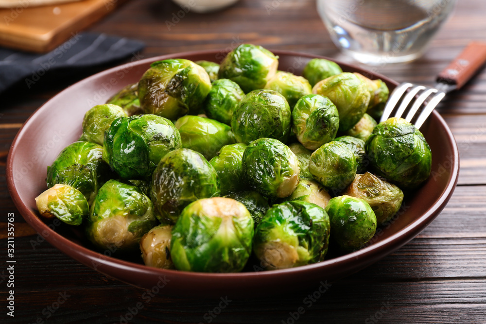 Roasted Brussels sprouts in plate on wooden table Roasted Brussels sprouts in plate on wooden table