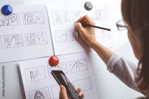 Woman draws a storyboard for an animated film on a white board.  photo