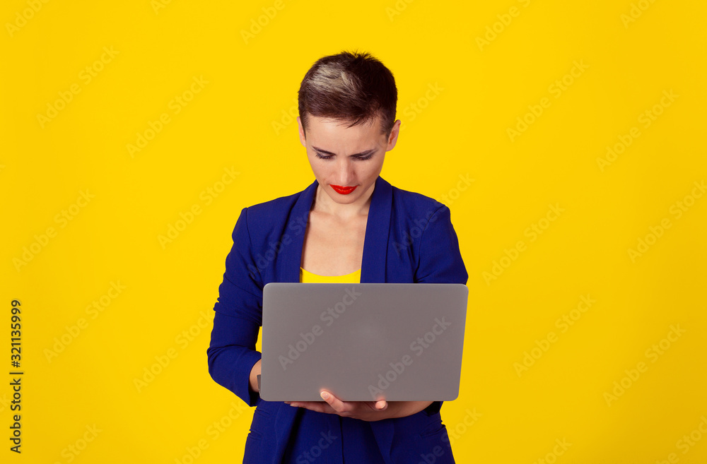 Serious woman working on computer isolated yellow background