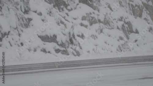 Full length of female athlete riding bicycle on road during snowfall