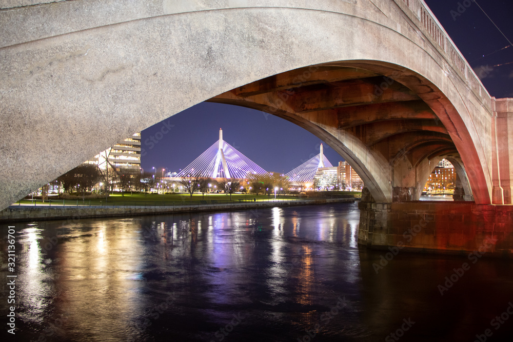Charles River and Bunker Hill Memorial Bridge (Modern Cable-Stayed Bridge) Framed by Arch of Concrete Bridge at Night - Boston, Massachusetts, USA
