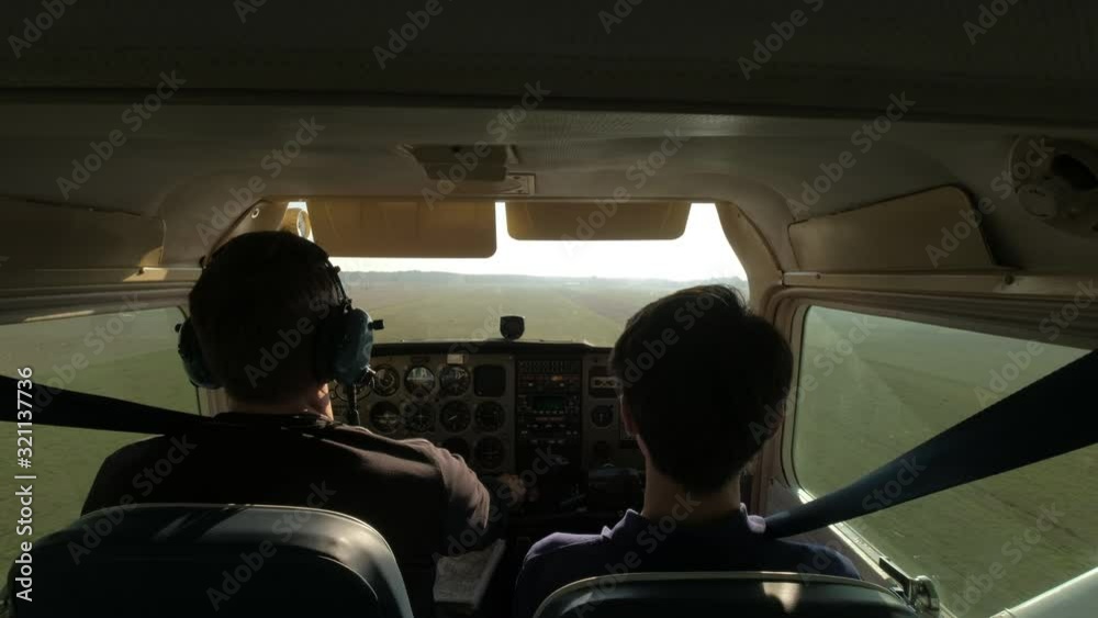 Father and son in propellor airplane landing in sunny rural field Father and son in propellor airplane landing in sunny rural field