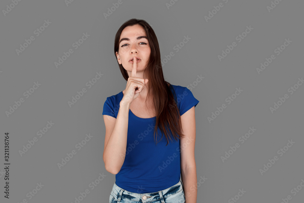 Young girl studio standing isolated on grey showing silence gesture serious Young girl studio standing isolated on grey showing silence gesture serious